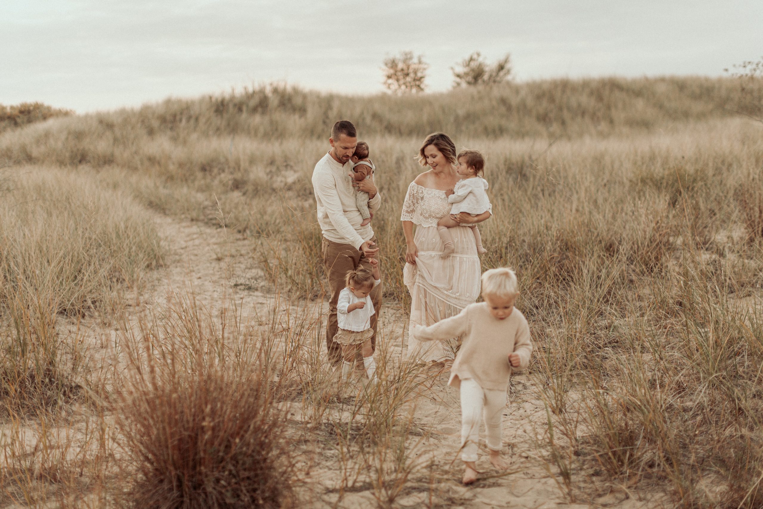 Family exploring in the dunes by lake michigan during a photoshoot wearing neutrals
