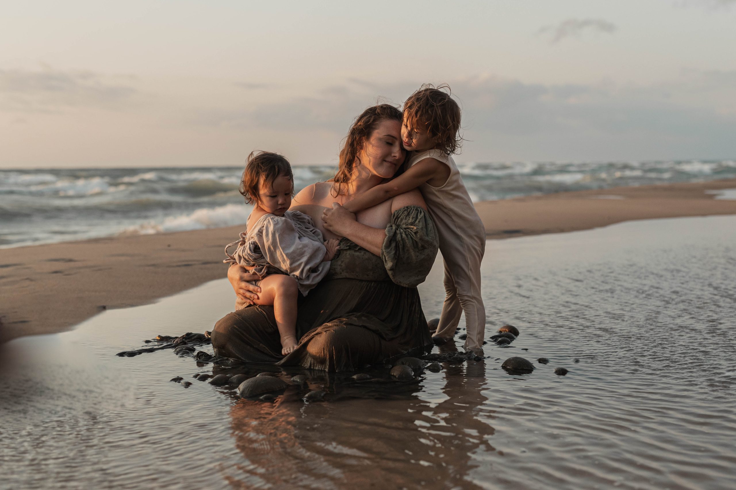 A mom shares a quiet moment with her son and daughter during a Lake Michigan photo shoot.