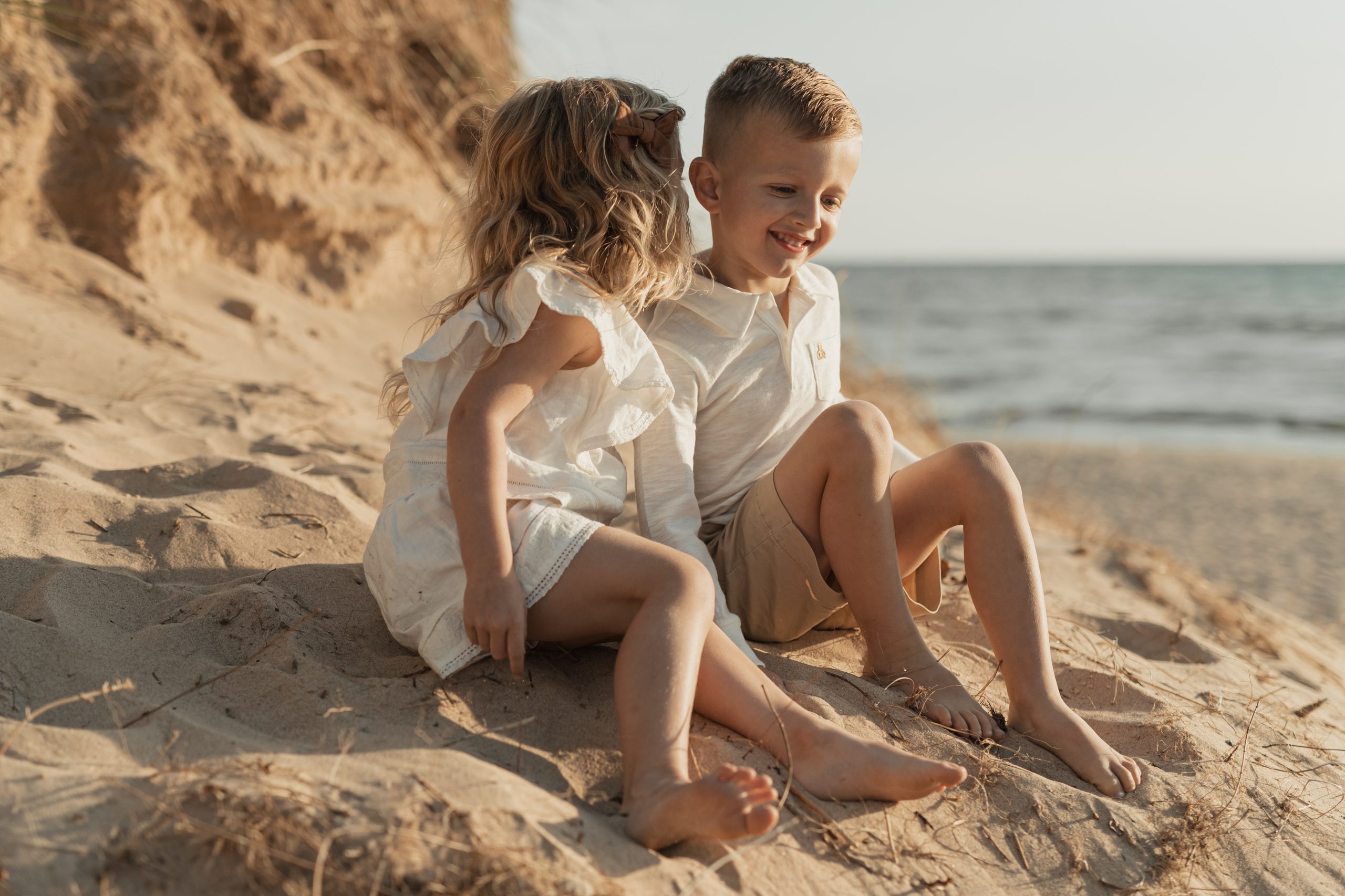 kids whispering to each other and laughing by lake michigan during a family session