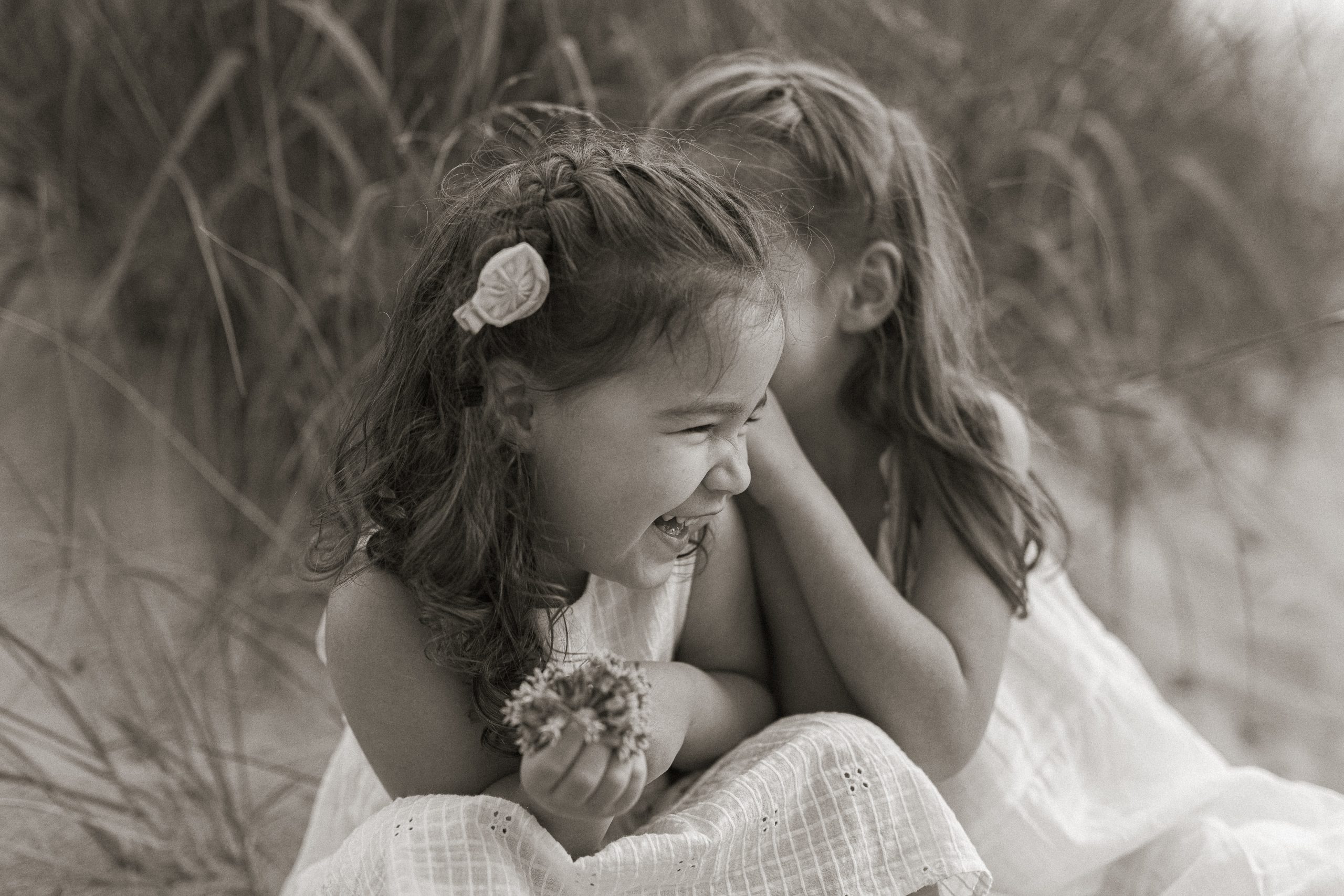 little girls laughing and playing on the dunes at lake michigan during a family photo session