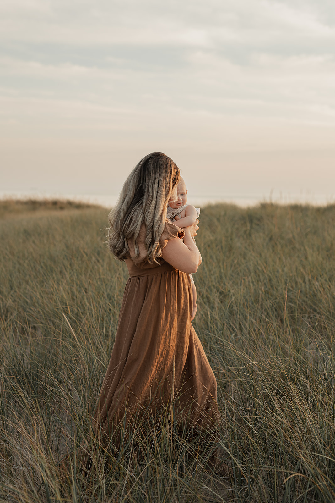 A mother holding her baby while walking outdoors, faces turned away