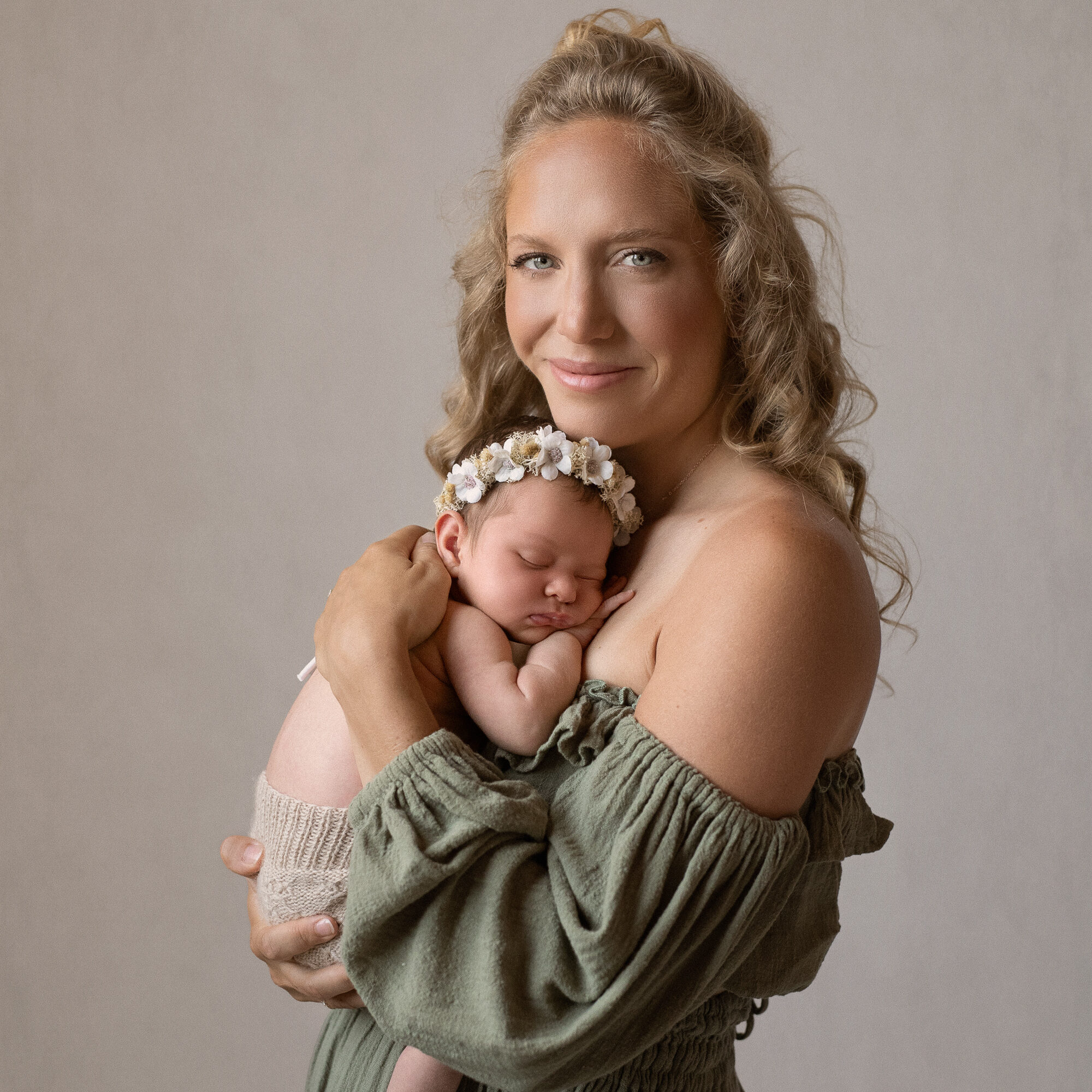 mom wearing sage green flowy dress holding her baby during newborn session with west mi photographer alissa saylor
