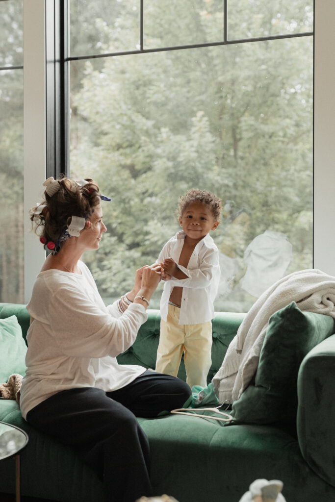 Mom helping her son get dressed during a family photo session at home in Michigan with Alissa Saylor