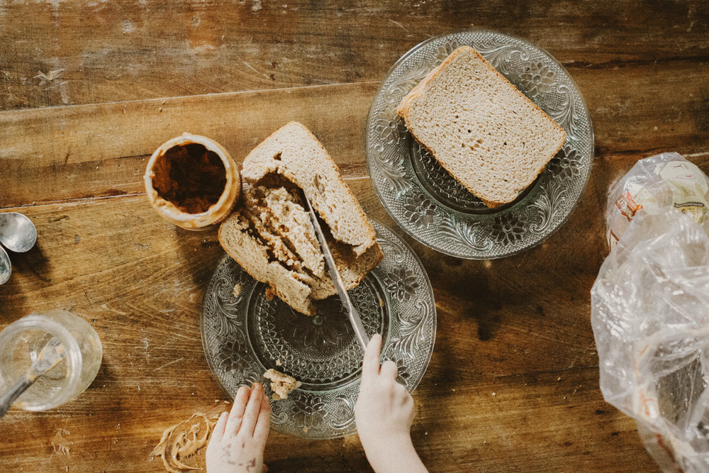 little kid hands trying to cut a sandwich during an in-home lifestyle session with Michigan family photographer Alissa Saylor