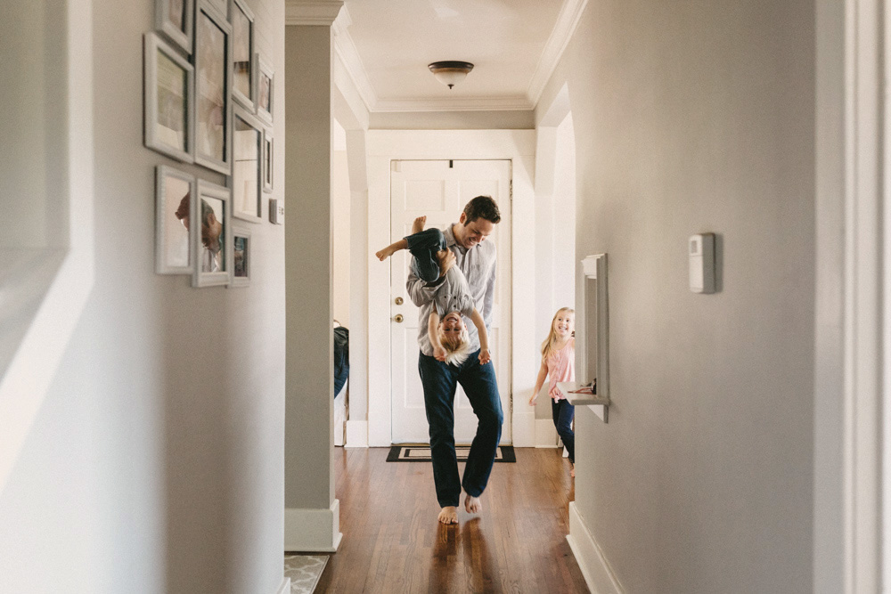 Dad playing with his children in the hallway of his house during a family photoshoot